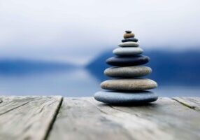 Zen balancing pebbles next to a misty lake.